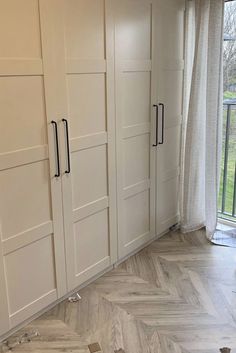 an empty room with white cabinets and wood flooring in front of a sliding glass door