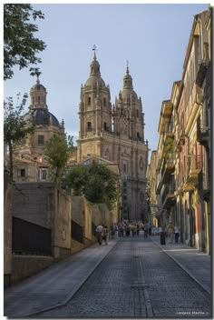 people are walking down the street in front of some old buildings and tall cathedrals