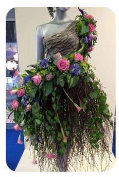 a dress made out of flowers and vines on display in a room with blue carpet