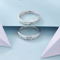 two silver rings sitting next to each other on top of a blue surface with origami