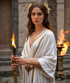 a woman dressed in white holding a stick with flames coming out of her hands and wearing a crown