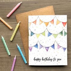 a birthday card with candles and confetti on the table next to it is an envelope that says happy birthday to you