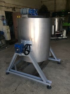 a large metal tank sitting on top of a stand in a garage next to other equipment