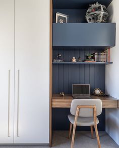 a desk with a laptop on top of it next to a book shelf and cupboard