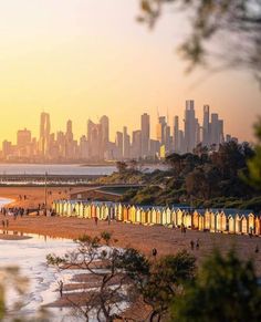 the beach is crowded with people and colorful buildings in the cityscape as the sun sets