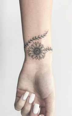 a woman's hand with a flower tattoo on the left side of her wrist