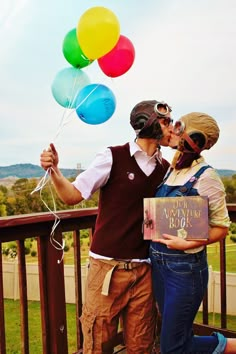 a man and woman kissing with balloons attached to their heads while standing on a deck