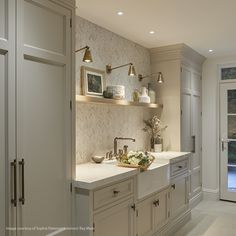 a kitchen with white cabinets and gold faucets