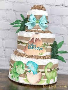 a three tiered diaper cake is decorated with dinosaurs, leaves and words on it