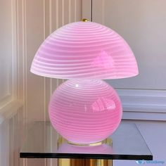 a pink lamp sitting on top of a table next to a white wall and door