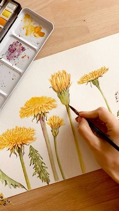 someone is painting yellow flowers with watercolors