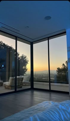 an empty bedroom with large windows overlooking the city at sunset or dawn, looking out onto the valley below