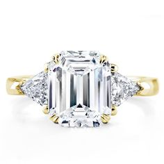 an emerald cut diamond ring with three diamonds on the side and two pear shaped sides