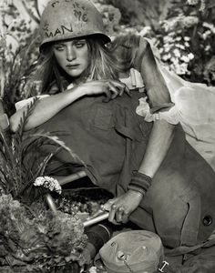 a black and white photo of a woman with a helmet on sitting in the grass