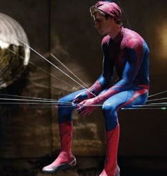 a man dressed as spider - man sitting on wires