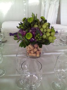 a vase filled with lots of green and purple flowers on top of a white table