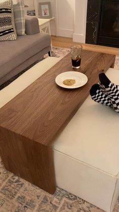 a person's feet resting on a bench in front of a coffee table and couch