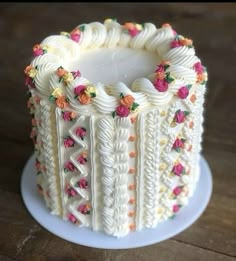 a cake with white frosting and colorful flowers on the top is sitting on a plate