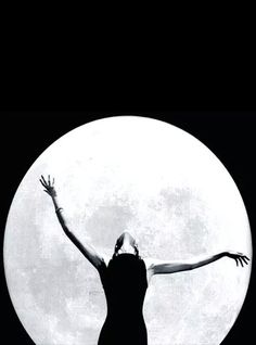 a black and white photo of a woman with her arms outstretched in front of a full moon