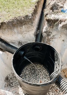 a bucket filled with gravel next to a pipe