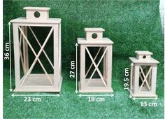 three white wooden lanterns with measurements for each one and the other two are on green grass