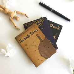 three children's books are sitting on a table next to a pen and doll