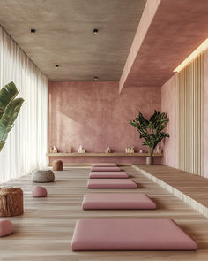 there are many pink yoga mats lined up on the floor in front of a plant