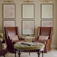 a living room with two chairs and a coffee table in front of three pictures on the wall