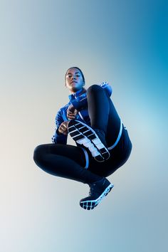 a woman in black and white outfit jumping up into the air