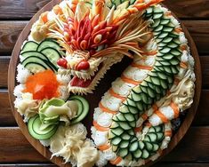 an elaborately decorated dragon cake on a wooden platter with cucumbers and carrots