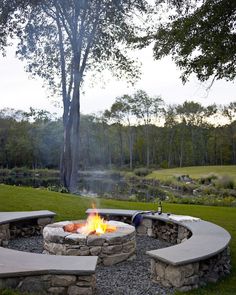 an outdoor fire pit with benches around it