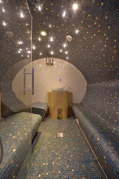 the inside of a bathroom with blue and gold mosaic tiles on the walls, along with two beds