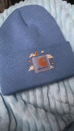 a blue beanie with an elephant patch on the front and bottom, sitting on top of a pile of blankets