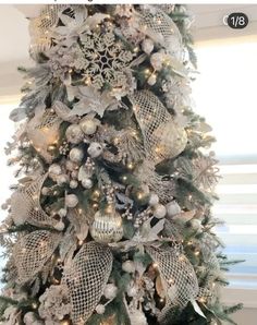 a white christmas tree with silver ornaments and lights