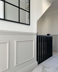 an empty hallway with white walls and black railings, mirrors on the wall above it