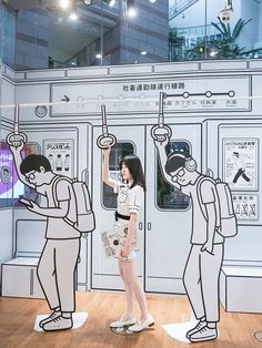 a woman standing in front of a drawing of two people on a subway train platform