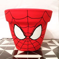 a spiderman pot sitting on top of a black and white tile floor next to a wall