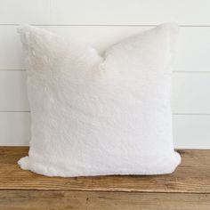 a white pillow sitting on top of a wooden table next to a wood plank wall