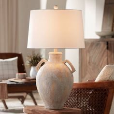 a table lamp sitting on top of a wooden stand next to a chair in a living room