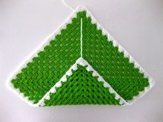 a crocheted ornament hanging on a wall with green and white trim