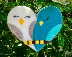 two blue and white birds hanging from a tree