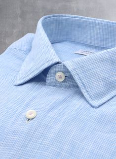 Inspired by the effortless style worn in Portofino, the Alexander in Light Blue Gingham Linen is a must-have of any wardrobe. Crafted of super soft linen fabric, it exudes effortless style when worn untucked. The pale purple stitching on the top collar button and cuffs adds a polished finishing touch. Worn under a suit and with a tie, the shirt exudes casual ease. The Alexander is the trimmest of all our fits, calibrated to accentuate a lean, athletic body type. • Trimmest Fit • 100% Linen • Spr Spring Plaid Linen Shirt, Classic Plaid Linen Shirt, Blue Linen Shirt With Placket, Classic Blue Linen Shirt, Blue Linen Shirt For Daywear, Fitted Blue Linen Shirt, Blue Linen Tops For Business Casual, Light Blue Linen Button-up Shirt, Spring Gingham Shirt With Spread Collar