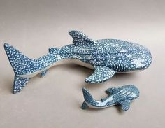 a blue and white ceramic figurine of a shark next to a smaller one