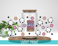 a glass jar filled with candy and ghost stickers next to a potted plant