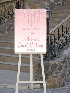 a welcome sign on a wooden easel in front of some stairs and stone steps