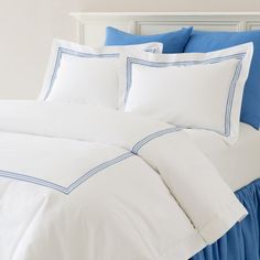 a bed with white and blue sheets and pillows