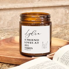 a jar of honey sitting on top of a wooden tray next to an open book