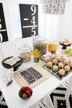 a white table topped with lots of desserts and snacks on top of it next to a black and white rug