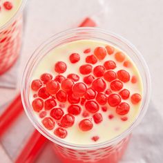 two cups filled with milk and red candies