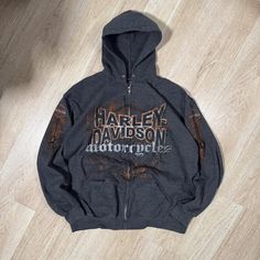 the harley davidson motorcycle hoodie is sitting on top of a wooden floor with it's zipper open